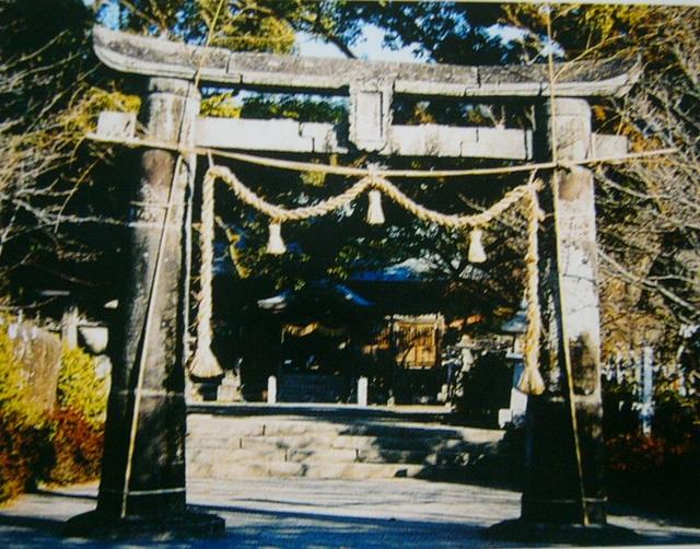 重厚な石造りの鳥居が神社の入り口に堂々と立ち、しめ縄と紙垂が飾られ、奥へと続く石畳の参道の先には木々に囲まれた社殿が静かに佇んでいる与止日女神社三ノ鳥居の写真
