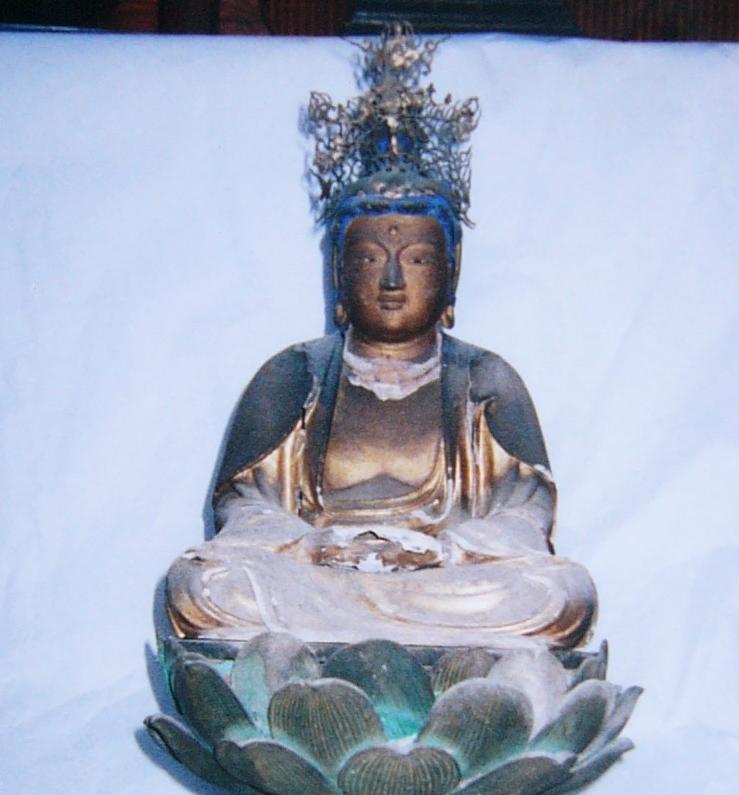 精緻な金属冠を戴く坐像が光沢を帯びた衣文を柔らかく広げて蓮華座上に静かに結跏趺坐し、落ち着いた気品と優雅な造形美を漂わせる写真