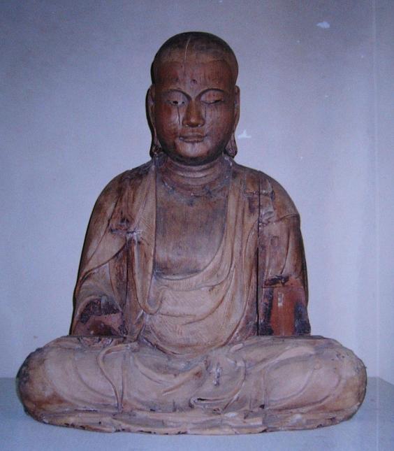 古色を帯びた木彫の坐像が穏やかな衣文の流れを見せつつ静かに結跏趺坐し全体に落ち着いた佇まいと時代を感じさせる風合いを漂わせる写真