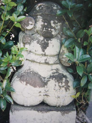 茂った緑に囲まれた苔むした石像が丸みある重厚な形状で静かに佇み、風化の模様が独特の質感を際立たせている写真