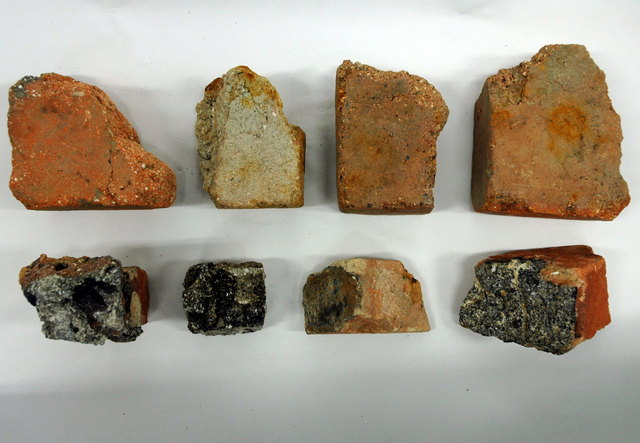 白や茶色の色味や質感が異なる、大小さまざまなレンガの破片が白い背景の上に上下二段に分かれて合計8個並べられており、それぞれの破片が持つ断面の模様や焼成具合の違いを真上から比較するように捉えた写真