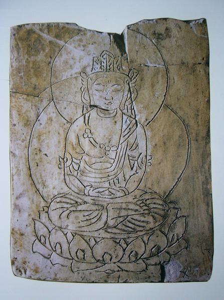 蓮華座の上で静かに目を閉じ、瞑想するような表情を浮かべた仏様が、複数の円光を背負った姿で平らな石の表面に繊細な線刻で描かれており、経年によるひび割れや色の変化が歴史の深さを物語る、石板に刻まれた仏画大日如来の写真