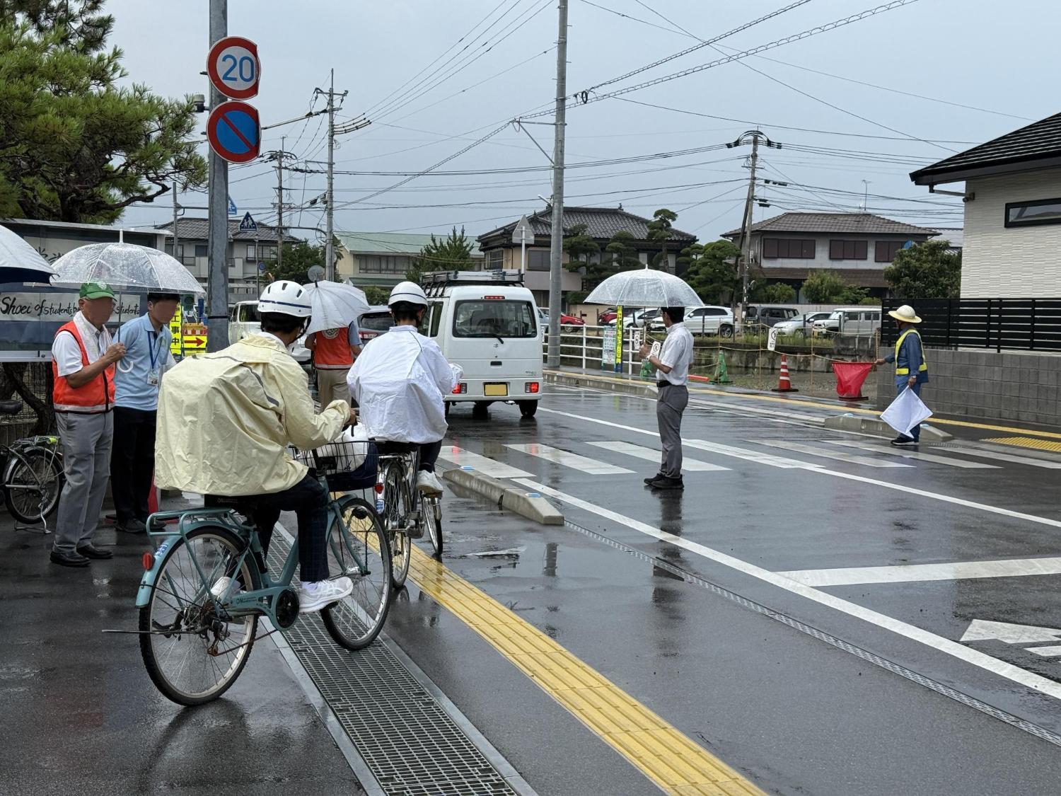 中学校の校門付近で、中学生の下校を、地区の青少年健全育成会の会員が安全確保のため、見守り活動を行っている。