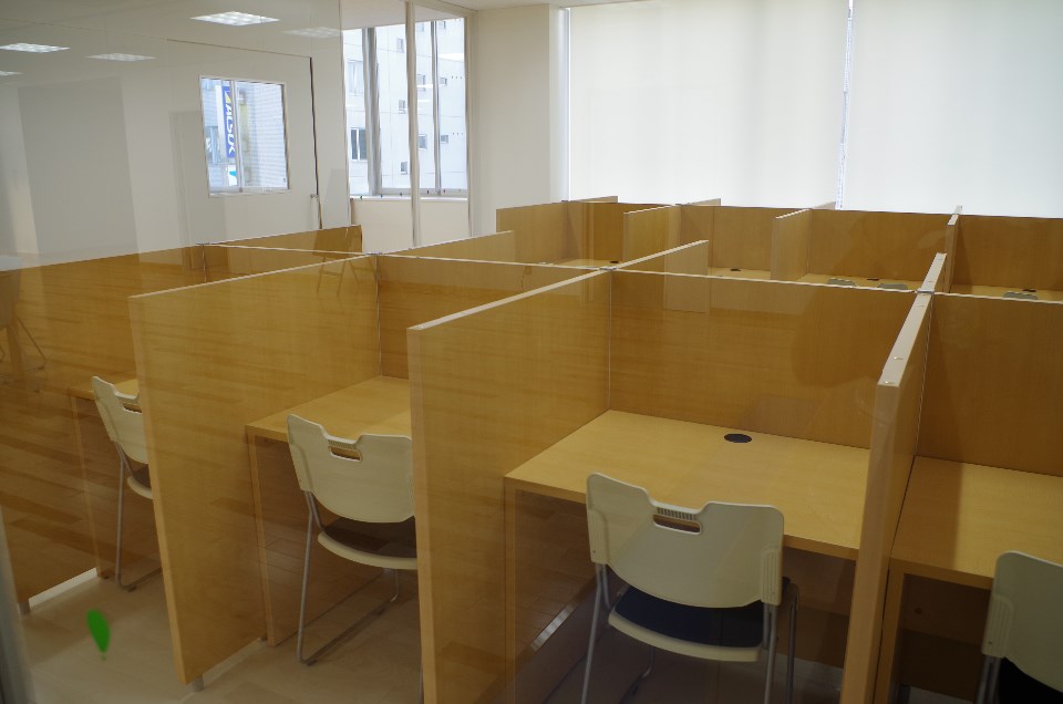 明るい室内に仕切り付きの木製デスクと白い椅子が規則正しく並び学習スペースとして整えられた様子を捉えた個別学習室の写真