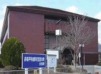 青空の下、手前に看板と植栽がある茶色い外壁の大和支所を正面から撮影した写真